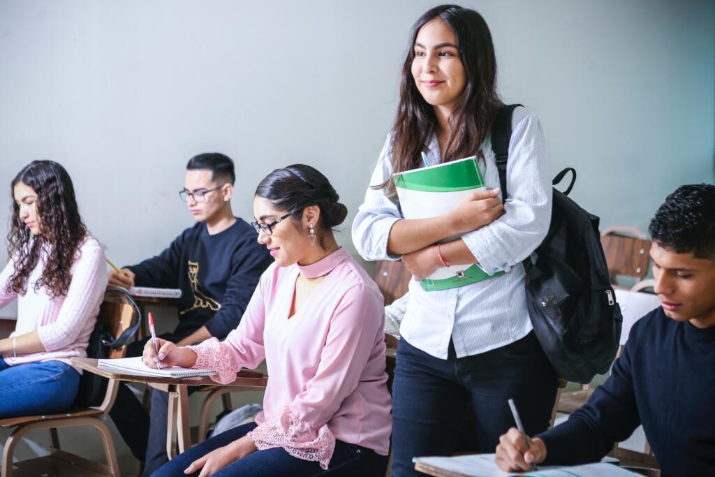 The university community is full of peer pressure or influence which students battle with. The picture shows a student standing whilst others are writing.
