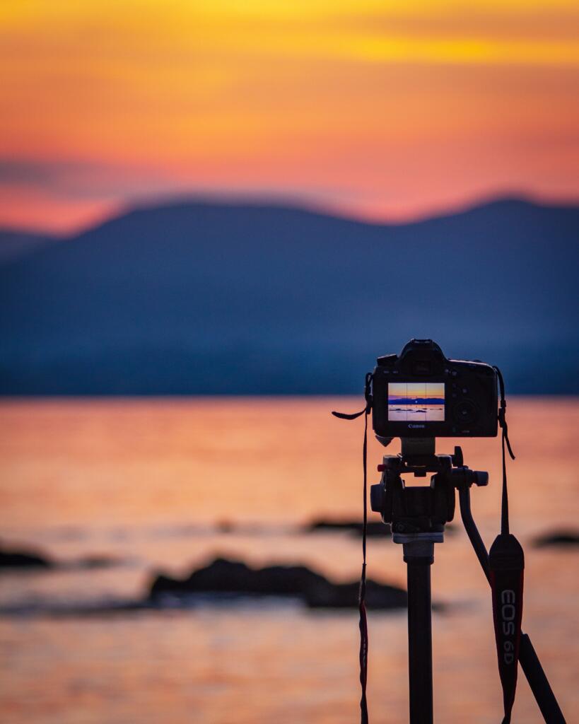 A camera standing on a tripod capturing the beautiful sunset clouds