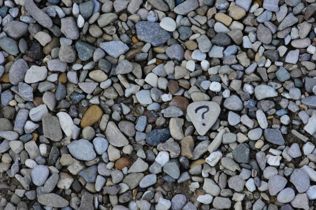 A question mark standing alone in the stones demonstrating how difficult coming up with a relevant research topic can be. 