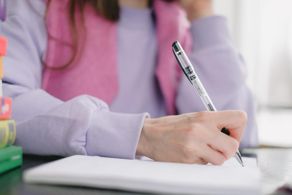 A serious student taking notes to write her personal statement for scholarship application. 